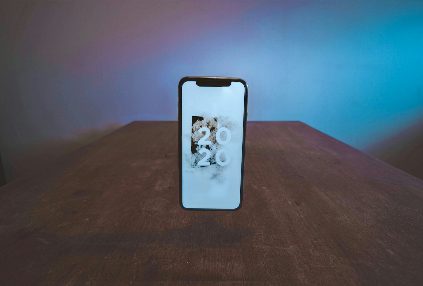 Smartphone displaying the year 2020 on a wooden table.